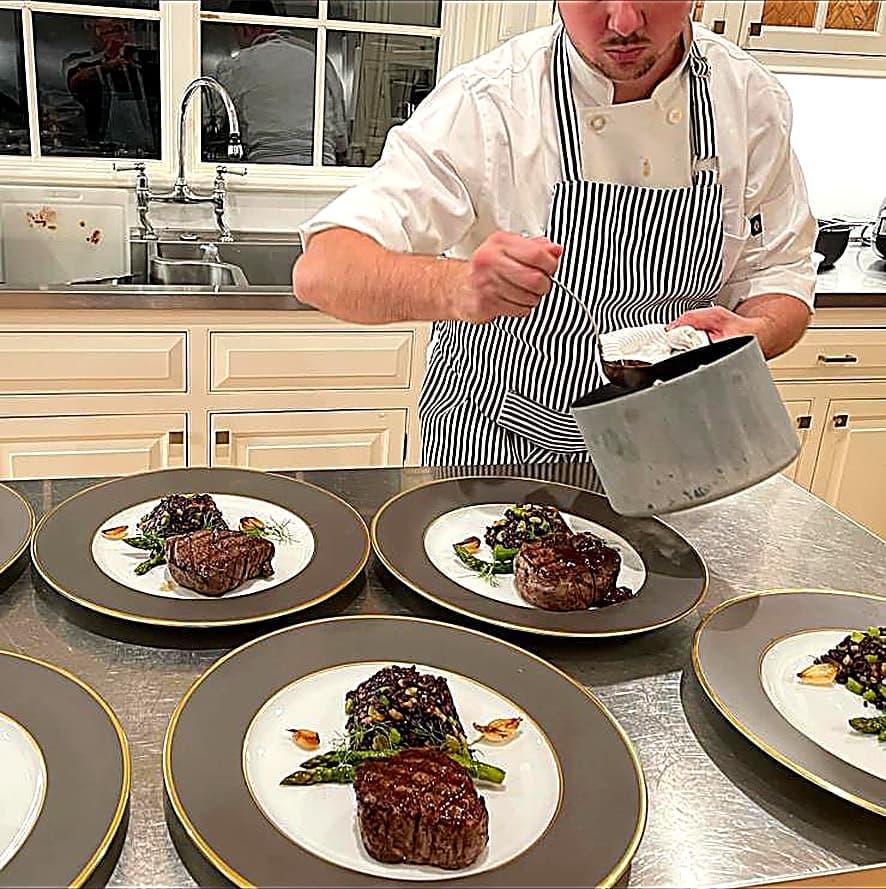 Chef plating filet mignon and asparagus