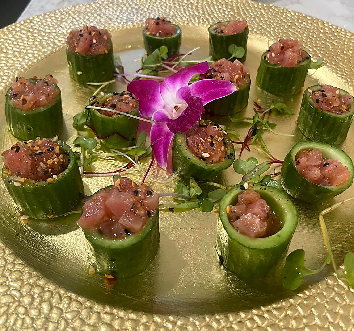 Tuna tartare in cucumber cups on a gold plate